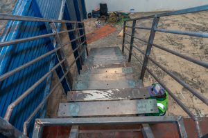 View down a metal staircase showing unfinished steps during commercial interior construction.