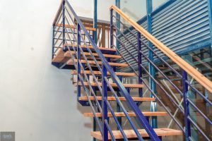 Metal staircase with wooden treads and handrails inside a commercial interior fit-out project.
